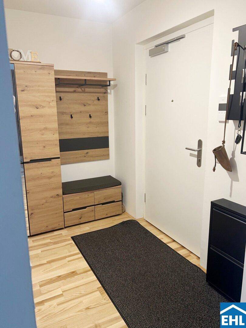 Heller Eingangsbereich mit Garderobe, Schuhschrank und ansprechendem Holzfußboden.