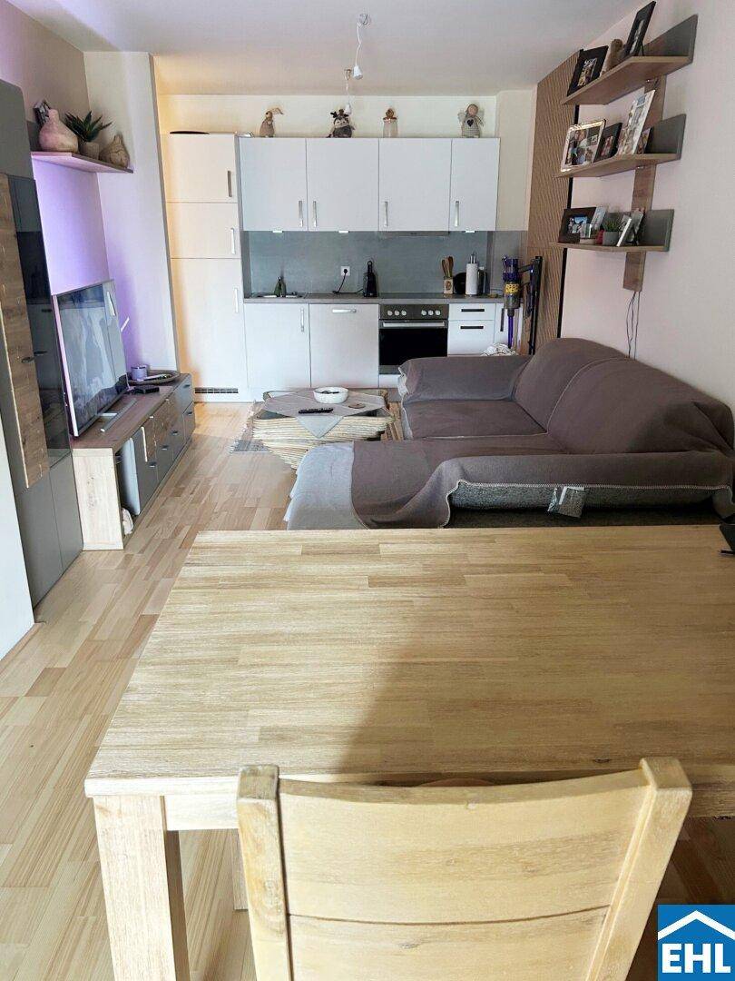 Heller Wohnbereich mit integrierter Küchenzeile, Sofa und Esstisch in offener Gestaltung.