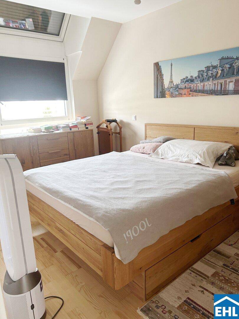 Gemütliches Schlafzimmer mit Holzbett, Dachschrägen und einem Dachfenster für natürliches Licht.