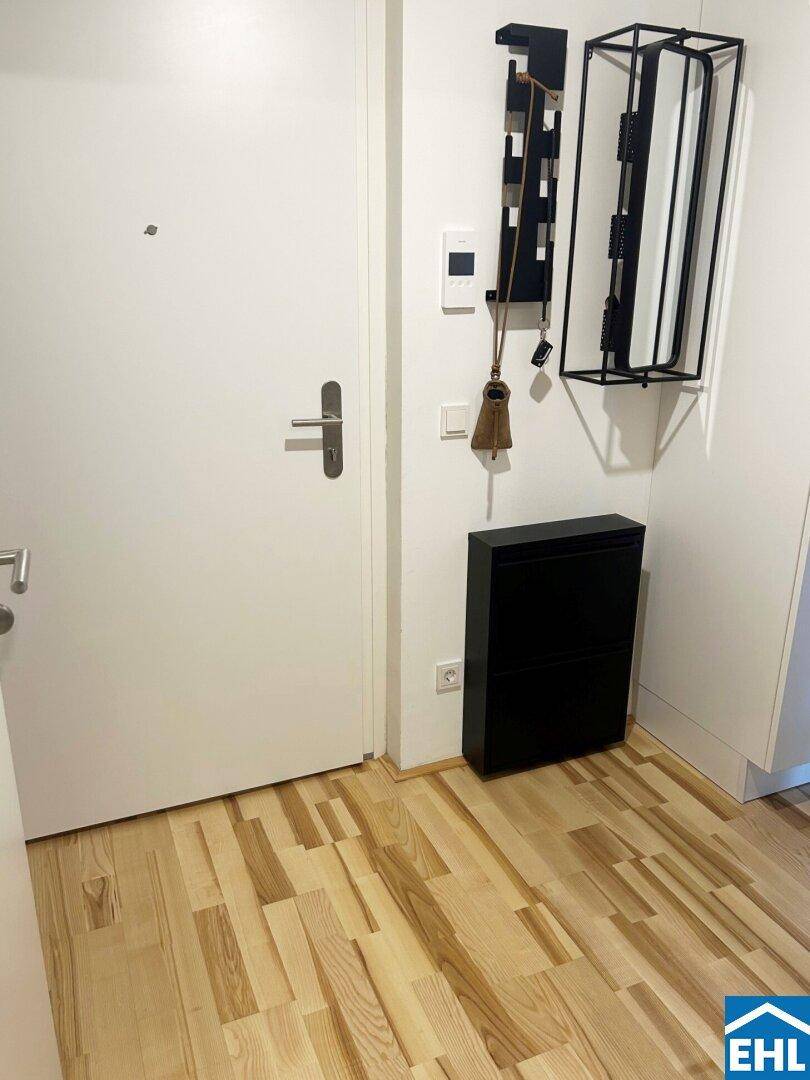 Eingangsbereich mit heller Tür, Schuhschrank und modernem Holzfußboden.