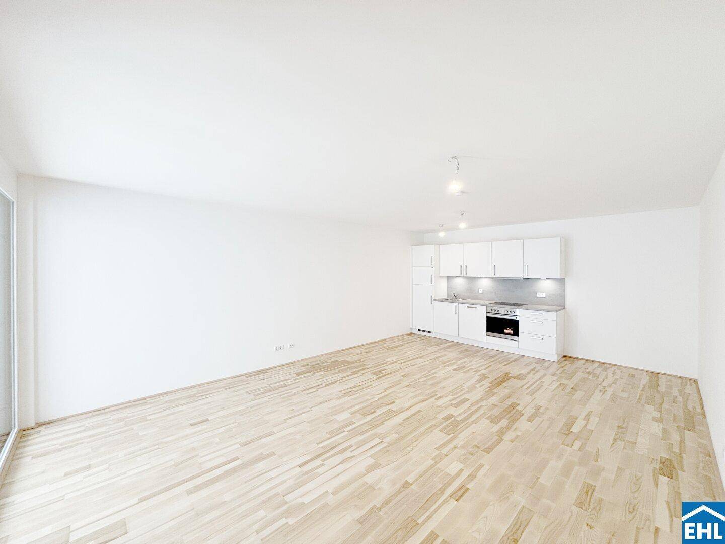 Moderne, weiße Küchenzeile mit integriertem Backofen und Spüle in einem hellen Raum.