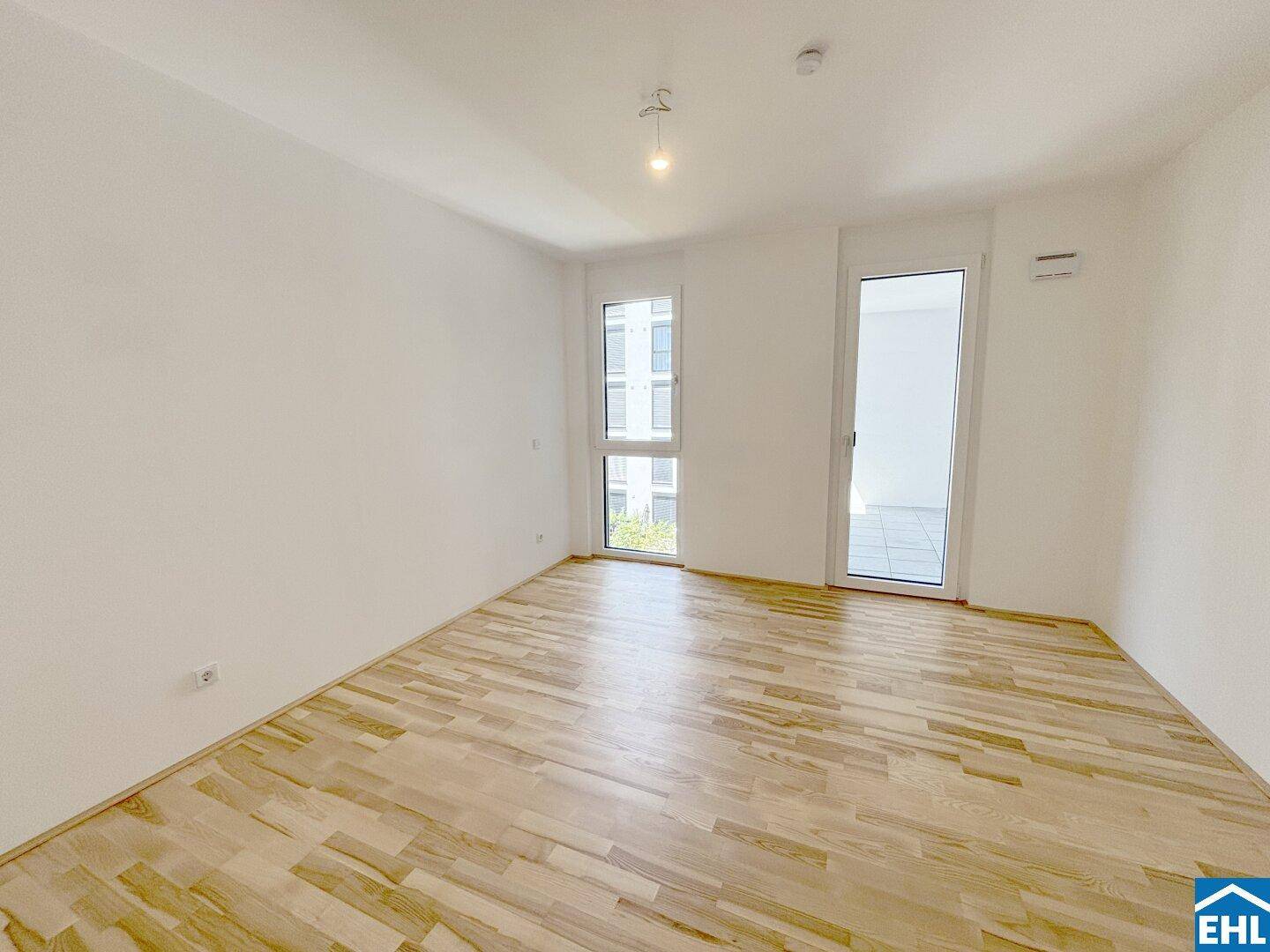 Helles Schlafzimmer mit Holzboden, großem Fenster und direktem Zugang zu einem Außenbereich.