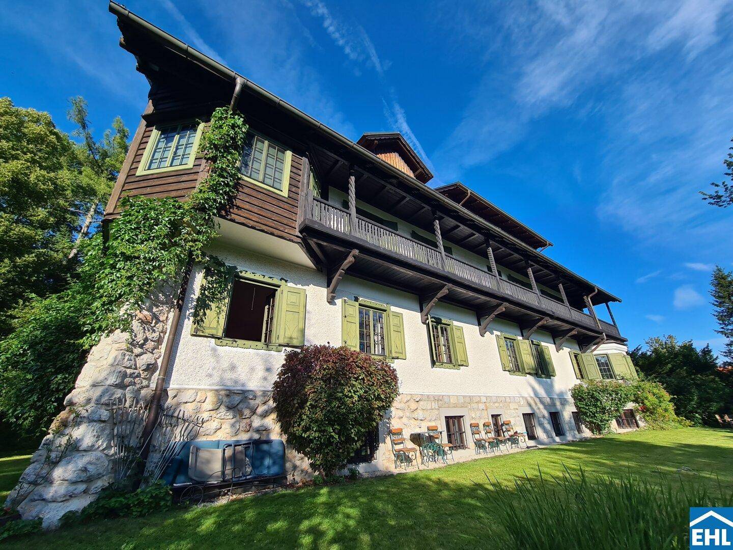 Seitenansicht des historischen Gebäudes mit rustikaler Steinfassade und grünen Fensterläden.