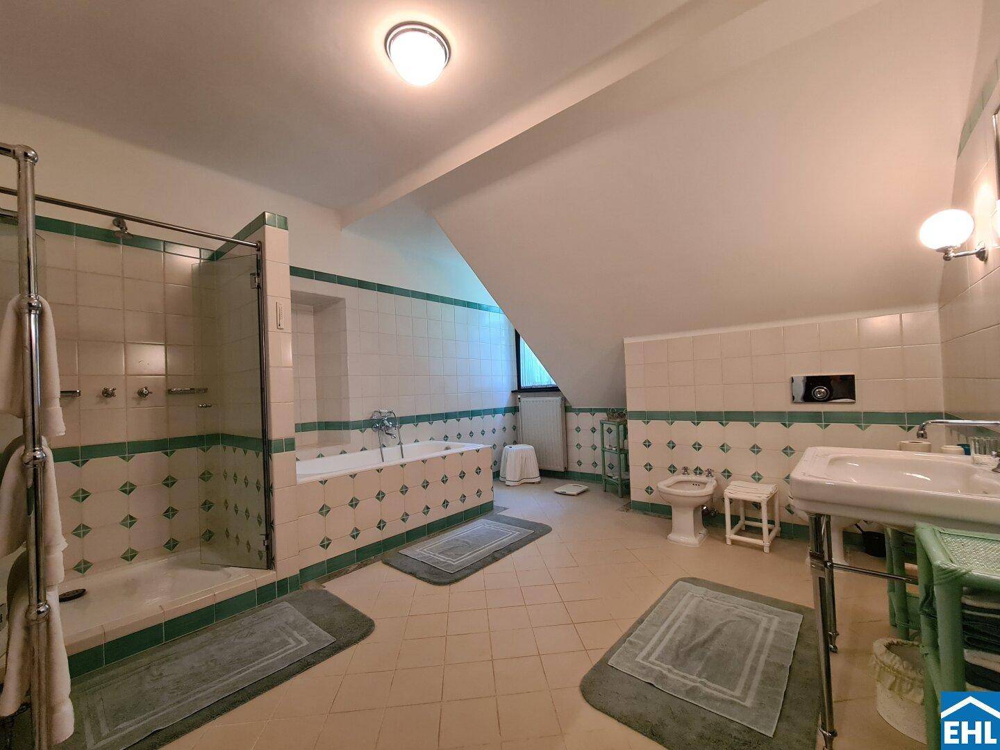 Geräumiges Badezimmer mit grünen und weißen Fliesen, Badewanne und separater Dusche.