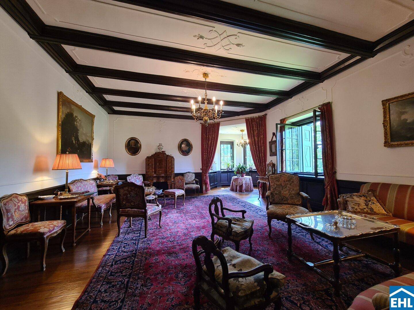 Elegantes Wohnzimmer mit Stuckdecke, Kronleuchter und antiken Möbeln in warmen Farbtönen.