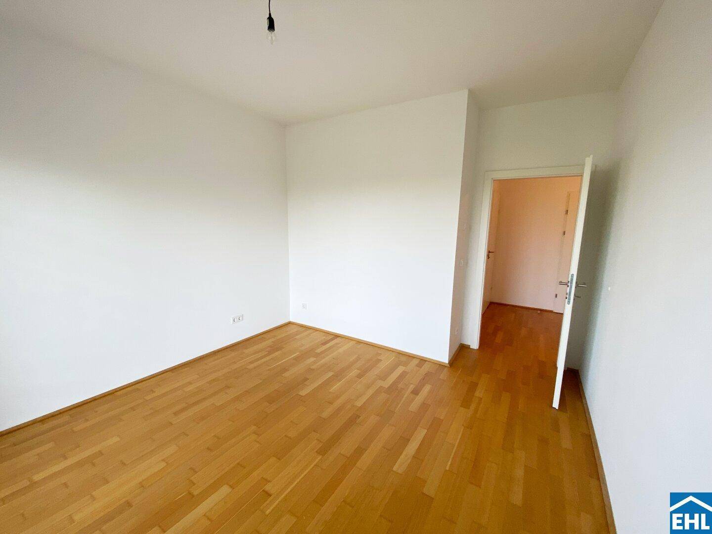 Leeres Zimmer mit Parkettboden und weiß gestrichenen Wänden, bereit zur individuellen Gestaltung.
