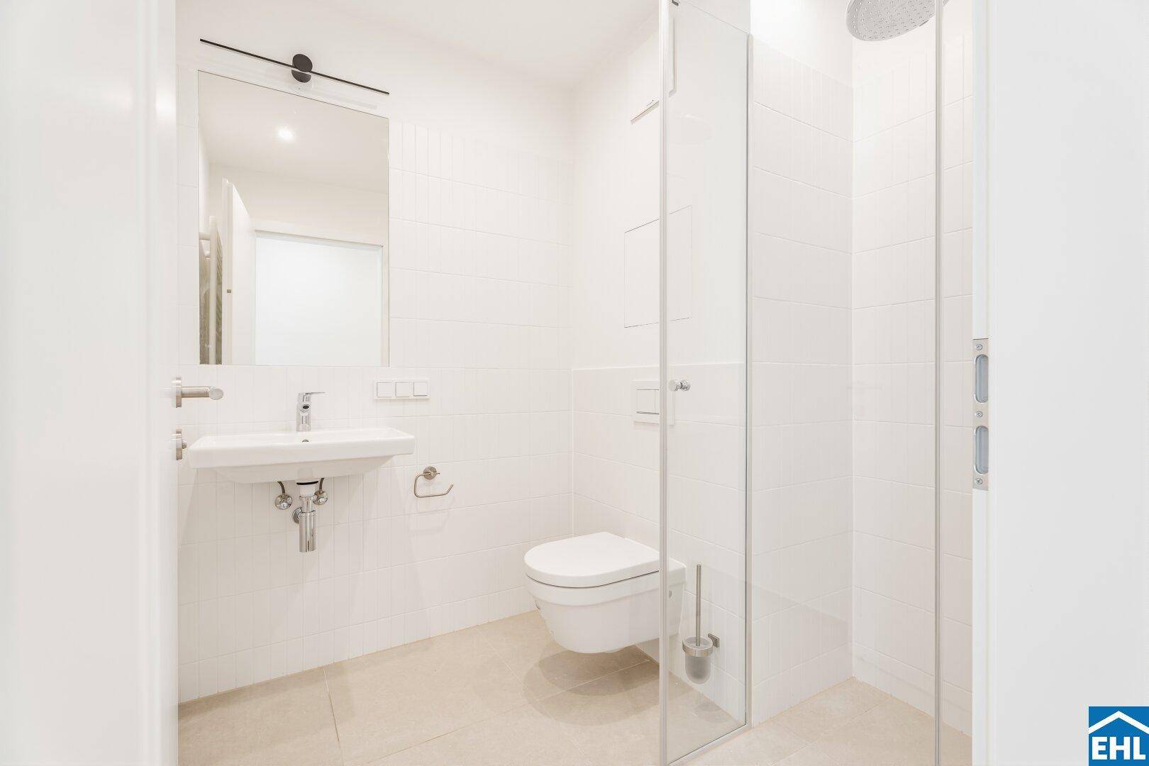 Helles Badezimmer mit wandhängendem WC, Einzelwaschbecken und moderner begehbarer Dusche.