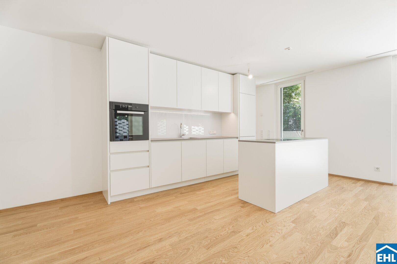 Moderne weiße Einbauküche mit integriertem Backofen und einer praktischen Kücheninsel.