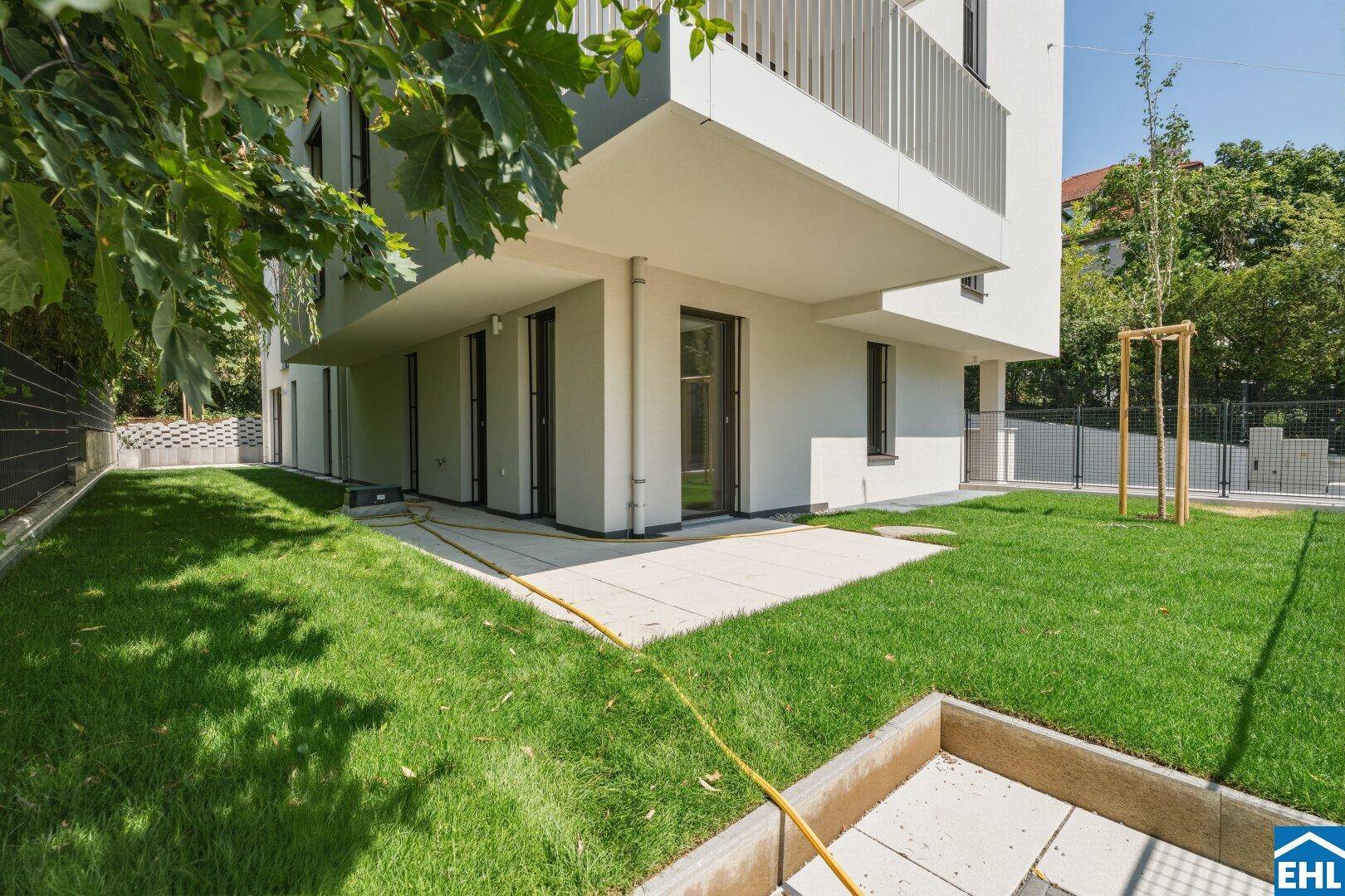Gepflegter Gartenbereich mit Rasenfläche und einer kleinen Terrasse am Gebäude.