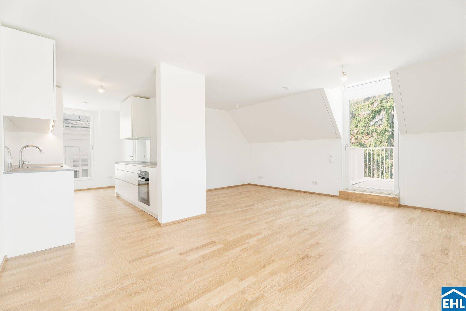 Offener Wohn- und Essbereich mit integrierter Küche, Holzboden und Zugang zu einem französischen Balkon.