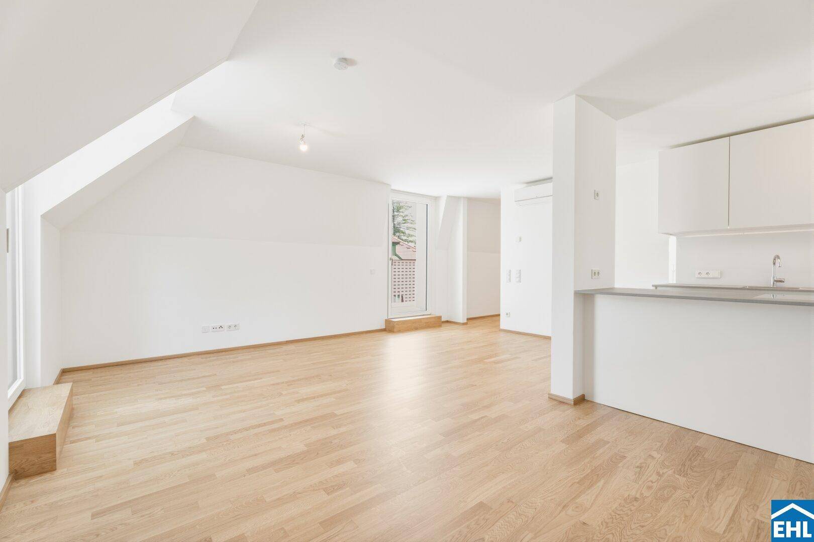 Heller Wohnbereich mit integrierter Küche, Frühstücksbar und Zugang zu einem französischen Balkon.