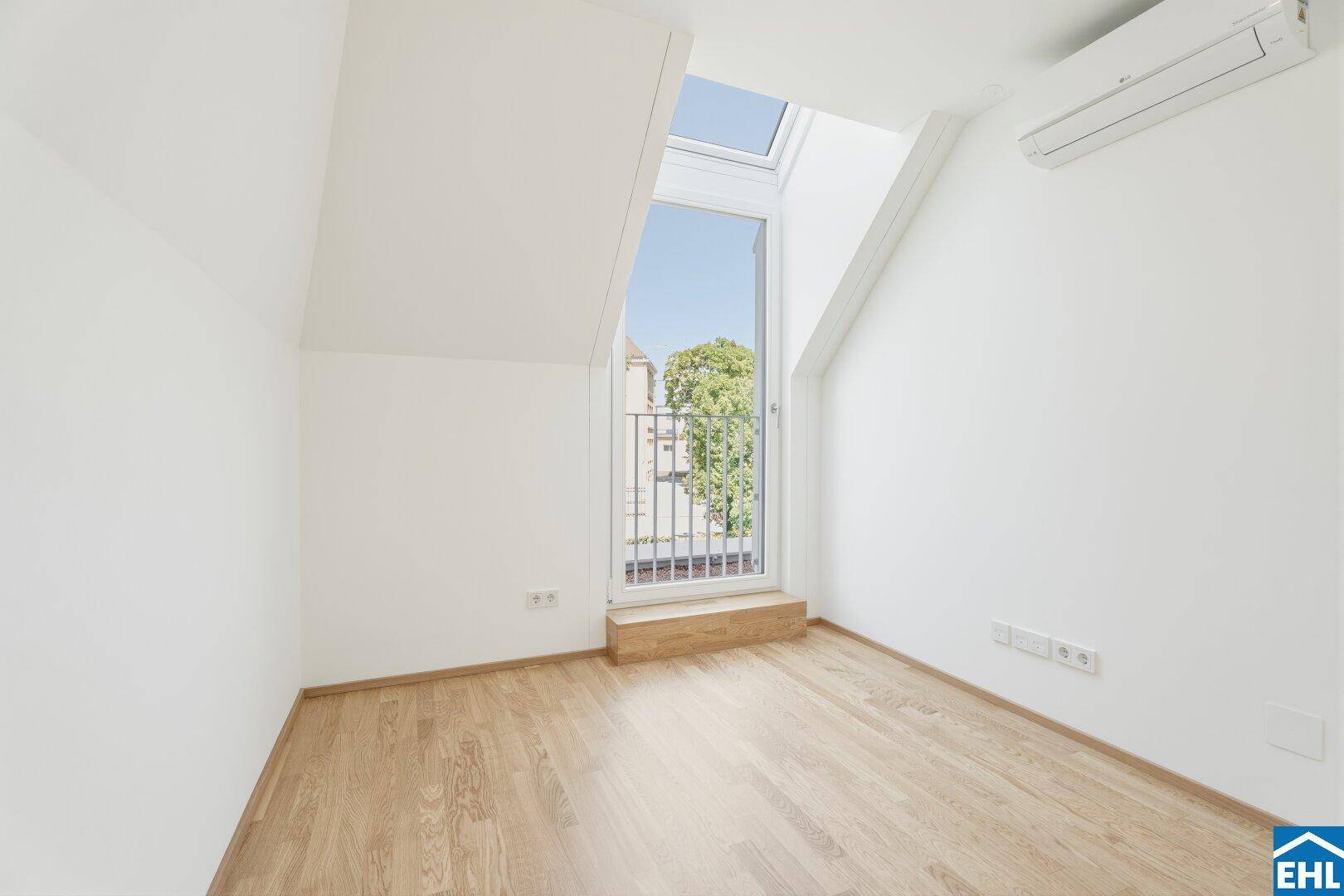 Heller Raum im Dachgeschoss mit Holzboden, Klimaanlage und französischem Balkon für viel Tageslicht.