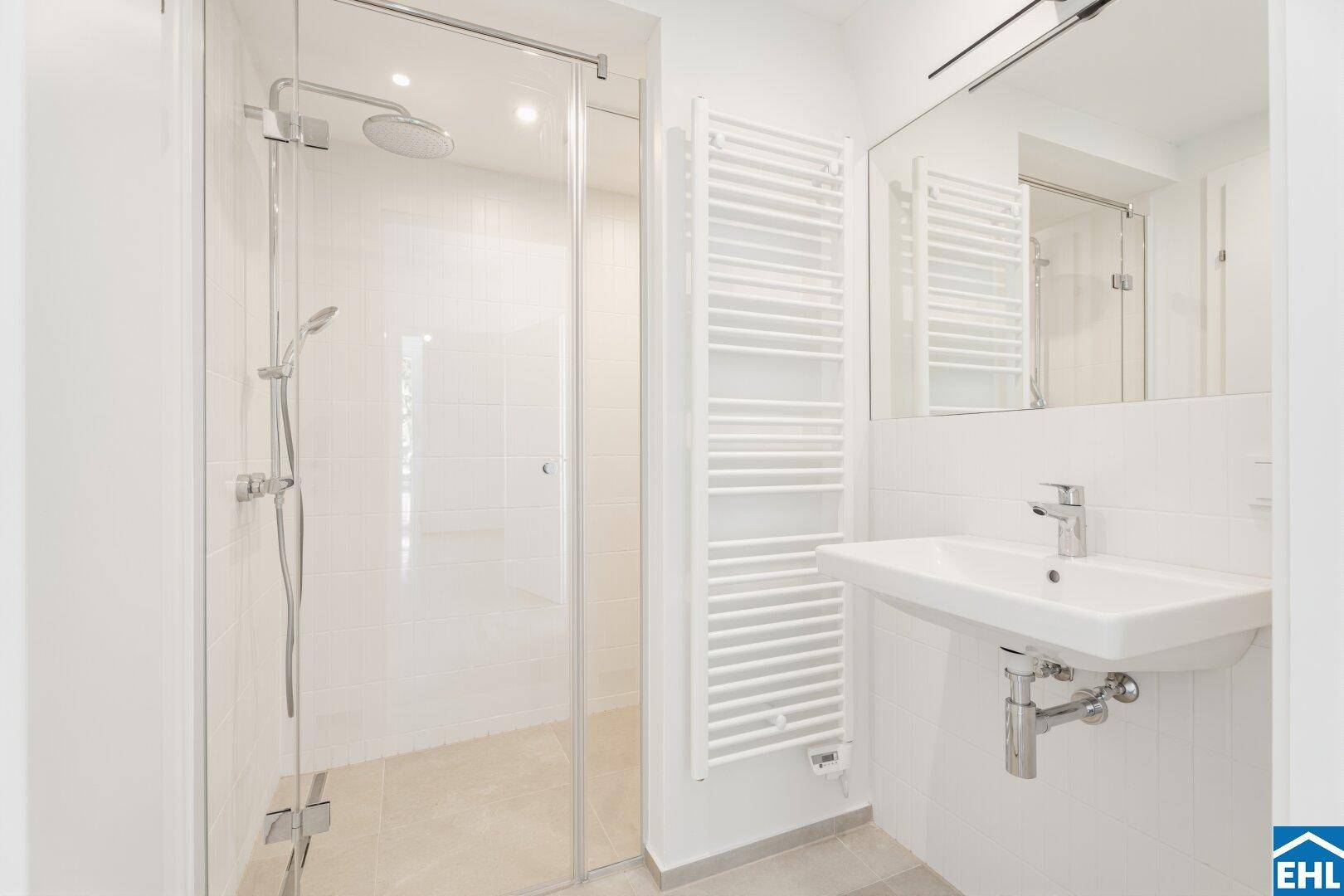 Modernes Badezimmer mit ebenerdiger Dusche, Einzelwaschbecken und beheiztem Handtuchhalter.