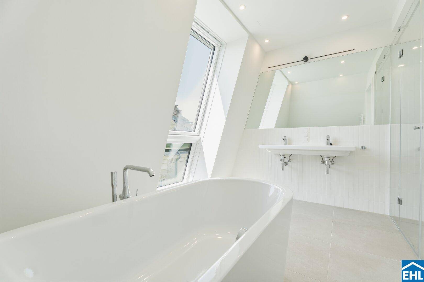 Luxuriöses Badezimmer mit freistehender Badewanne, Doppelwaschbecken und großem Dachfenster.