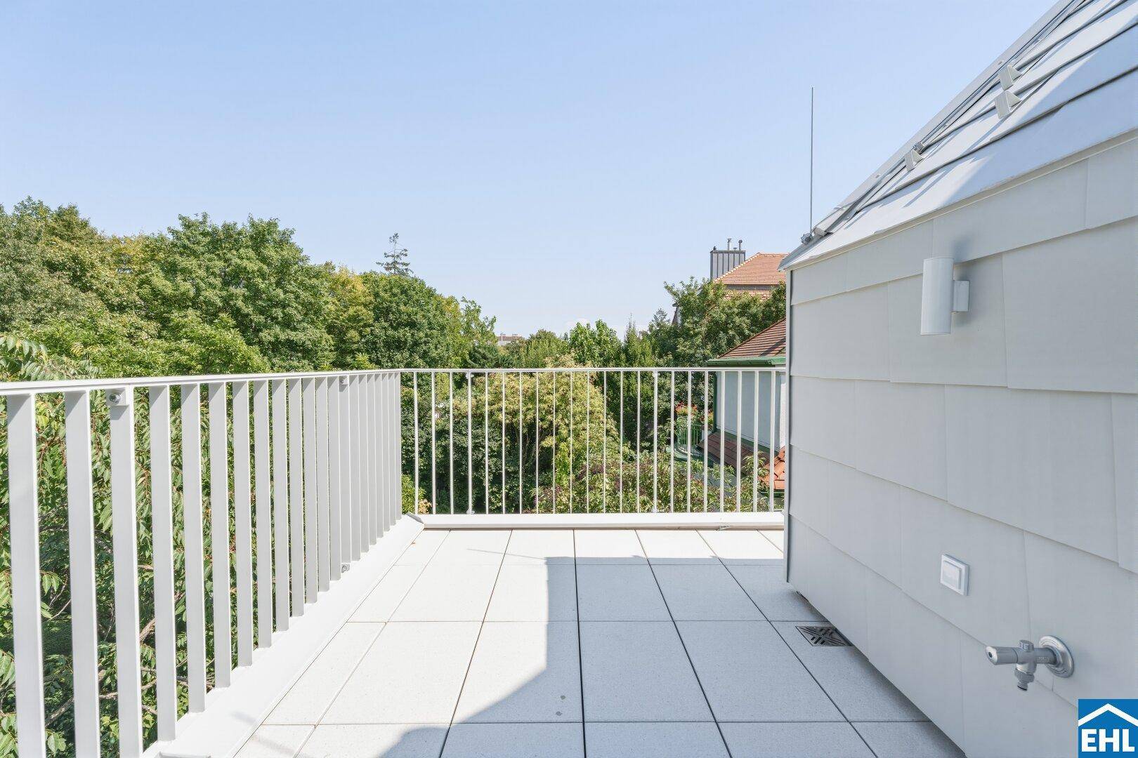 Große Dachterrasse mit Fliesenboden und weitem Blick über die Baumwipfel.