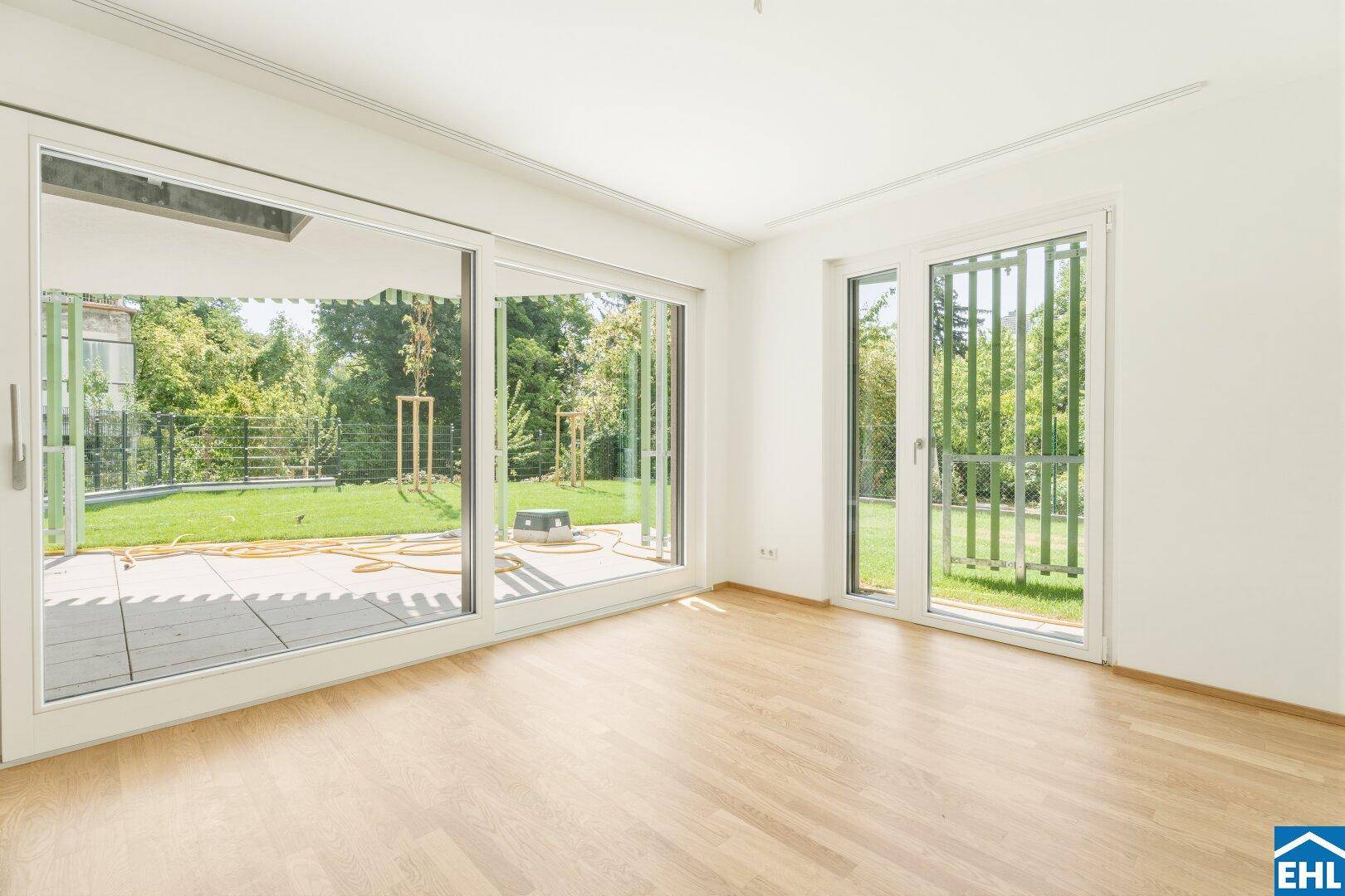 Lichtdurchflutetes Zimmer mit Holzboden und direktem Zugang zur Terrasse und zum Garten.
