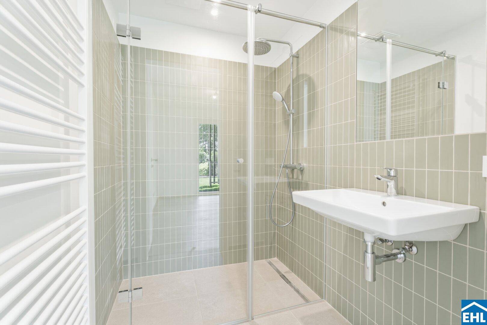 Modernes Badezimmer mit begehbarer Dusche, hellen Fliesen und Handtuchheizkörper.