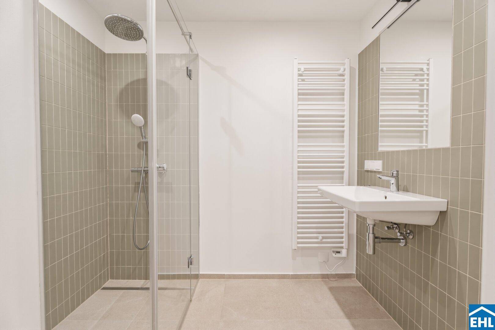 Modernes Badezimmer mit Dusche, Waschbecken und großem Spiegel, in neutralen Farbtönen gehalten.