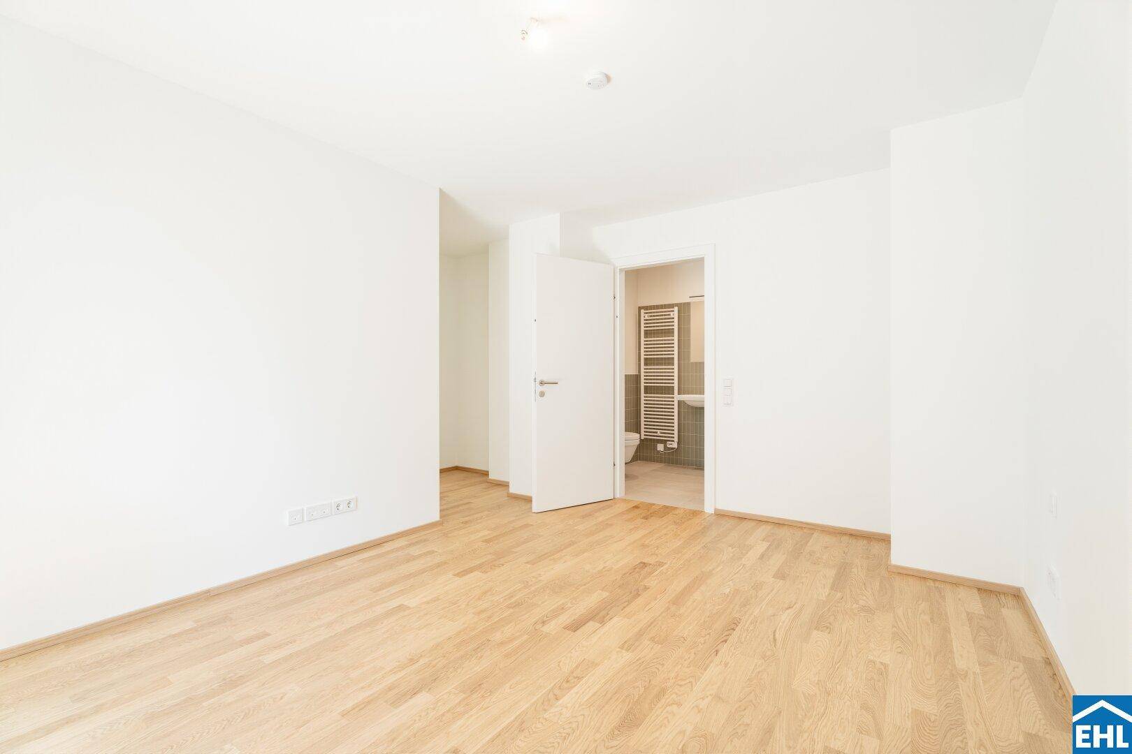 Geräumiges Zimmer mit Parkettboden und direktem Zugang zu einem modernen Badezimmer.