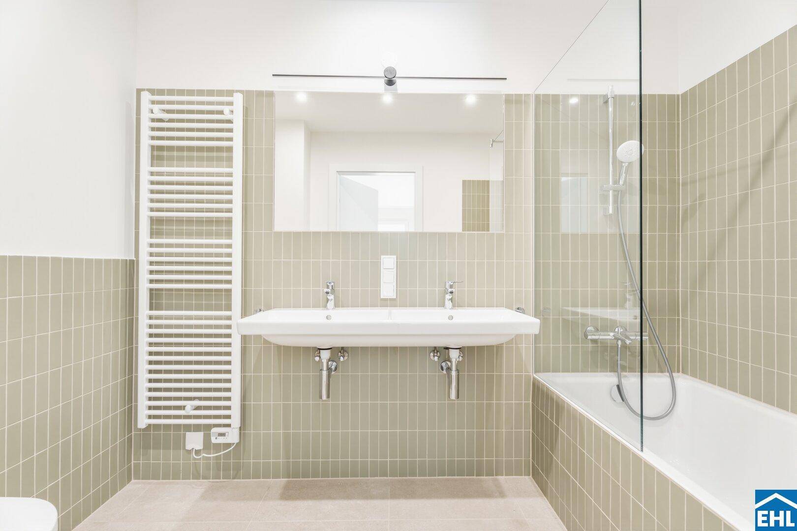 Modernes Badezimmer mit Doppelwaschbecken, Badewanne und Handtuchheizkörper.