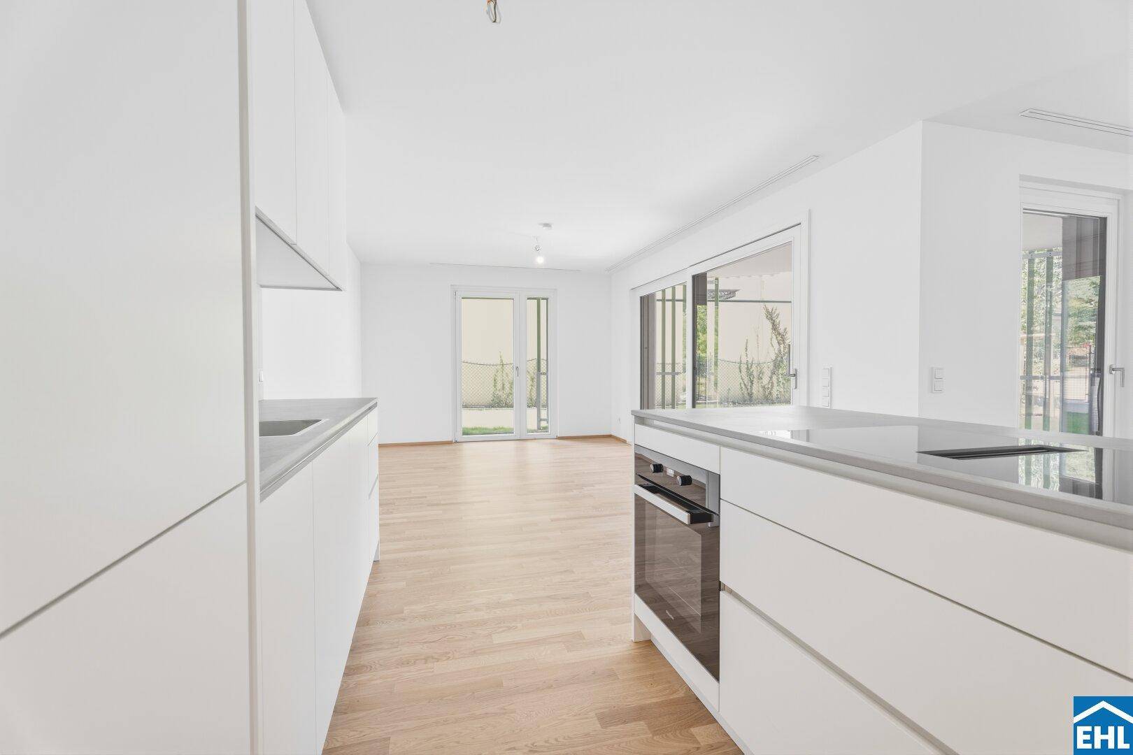 Moderne Küche mit Kochinsel und integriertem Backofen, offen zum Wohnbereich mit Gartenzugang.