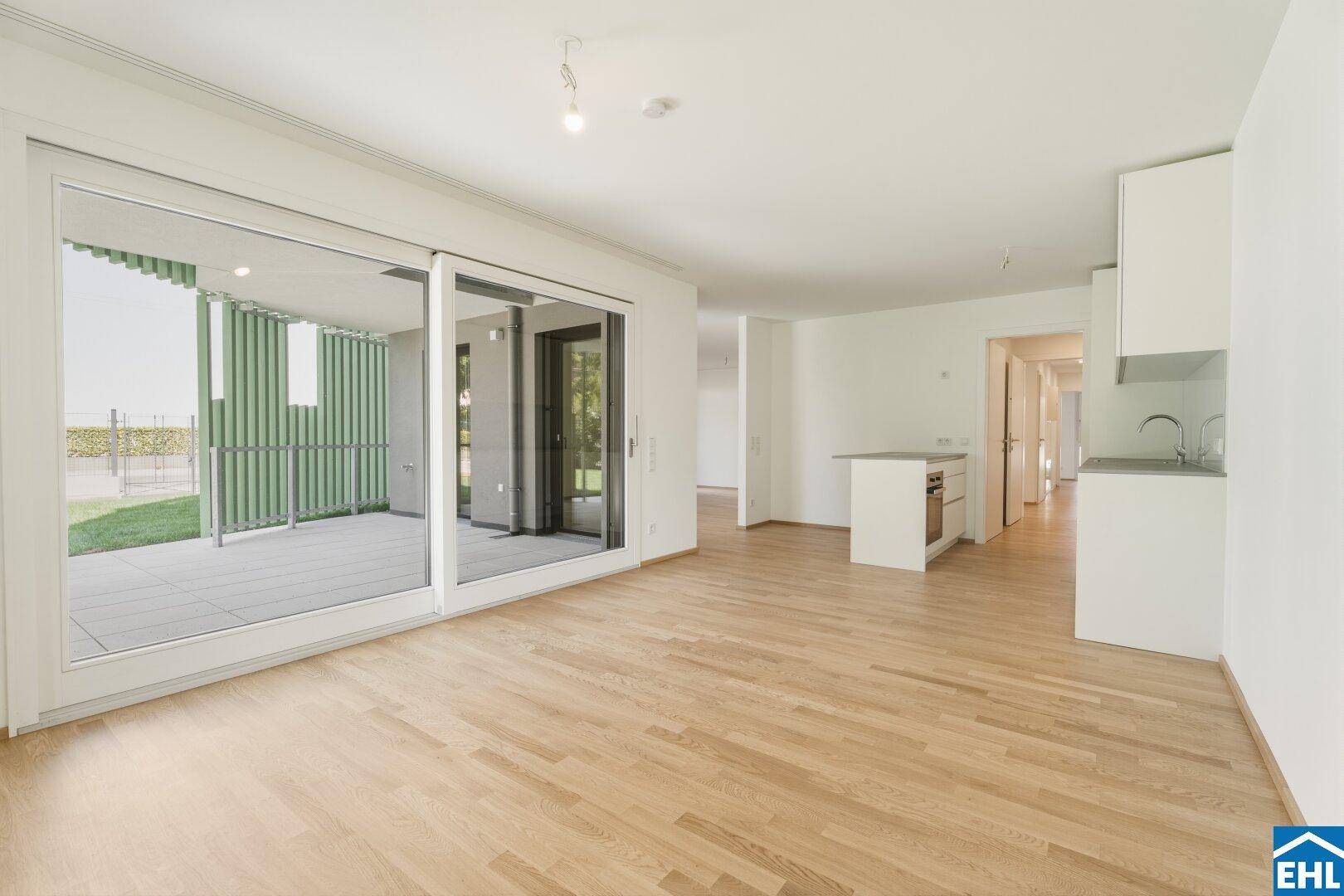 Heller, offener Wohnbereich mit integrierter Küche, Parkettboden und Zugang zur Terrasse.