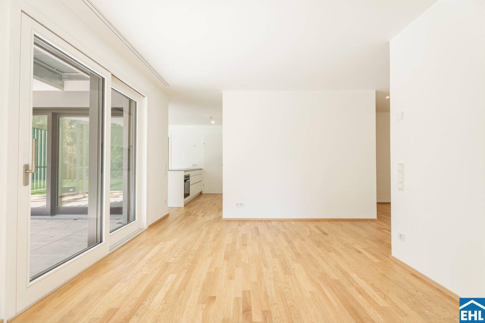 Offener Wohnbereich mit Parkettboden und Blick auf den Küchenbereich und den Garten.