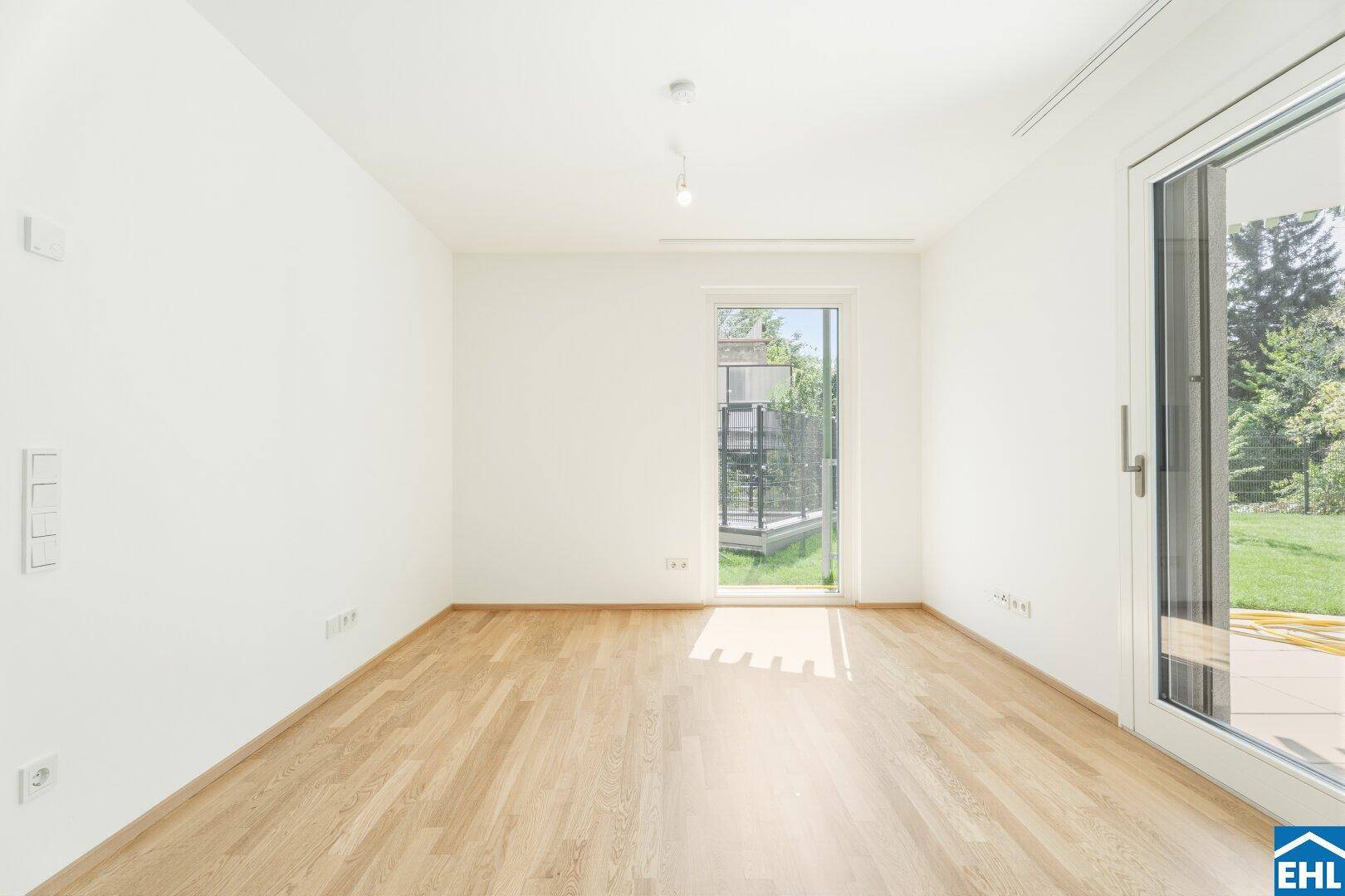 Helles Zimmer mit Parkettboden und direktem Zugang zu einem kleinen Außenbereich.