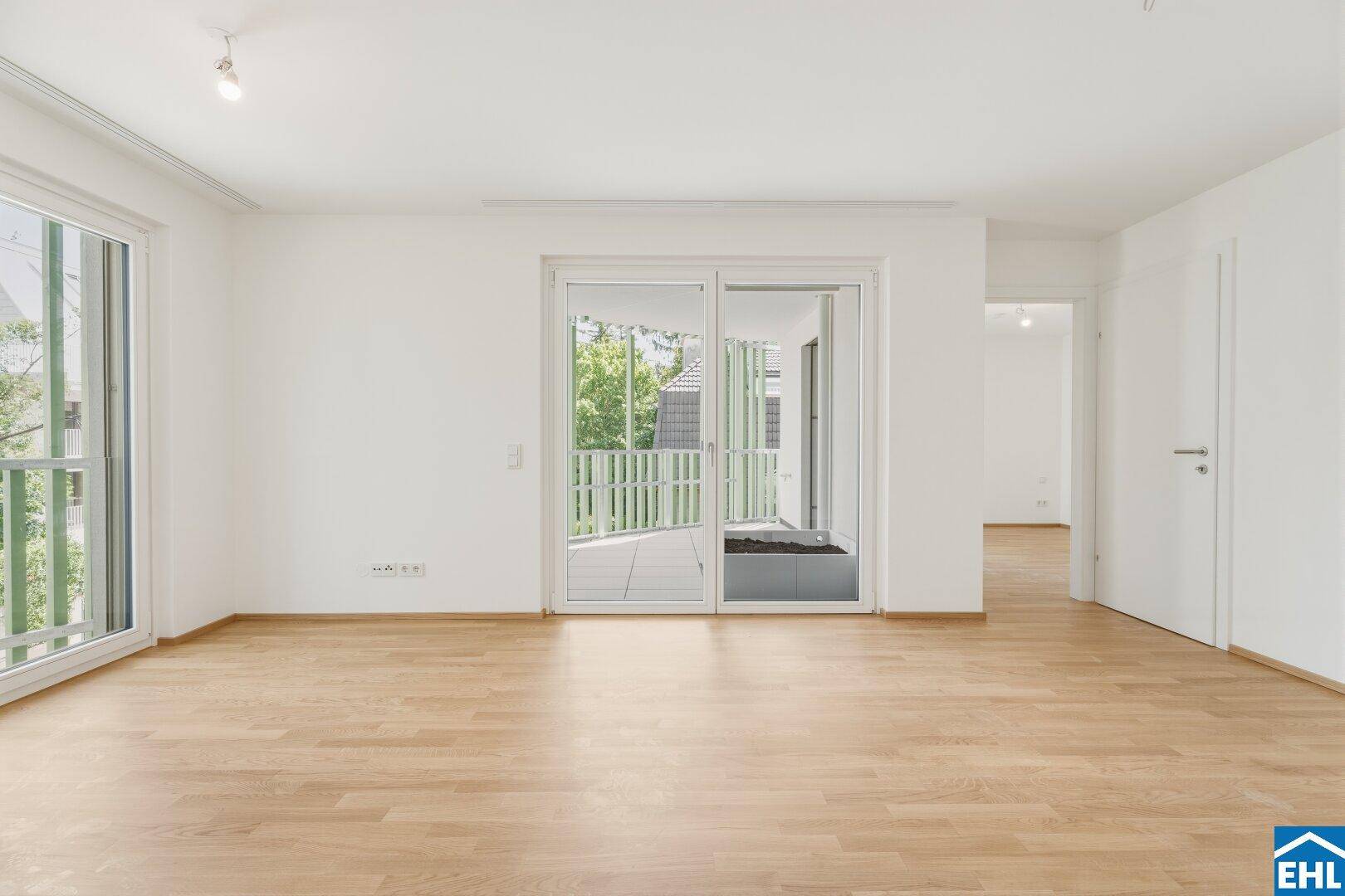 Heller Wohnbereich mit Parkettboden und Zugang zu einem Balkon, ideal für entspannte Stunden.