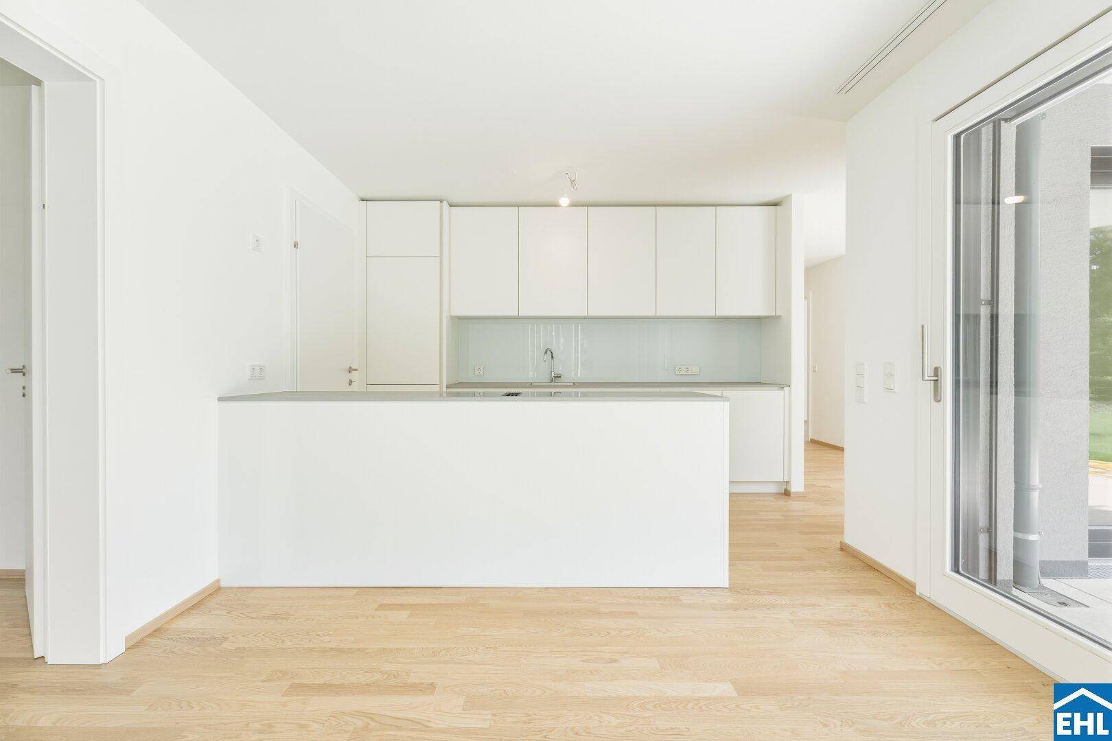 Offene Küche mit weißer Kücheninsel und modernen Schränken, verbunden mit dem Wohnbereich.