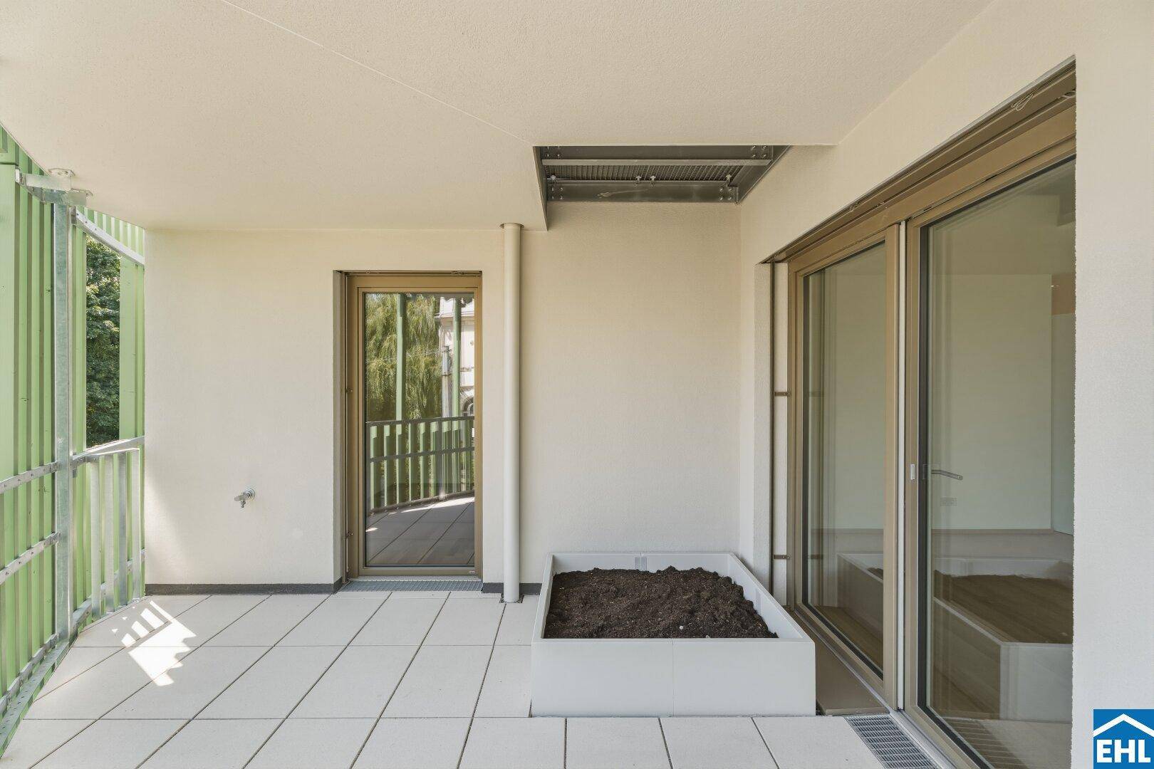 Geräumiger Balkon mit Fliesenboden, integriertem Pflanzbeet und Zugang zum Innenbereich.