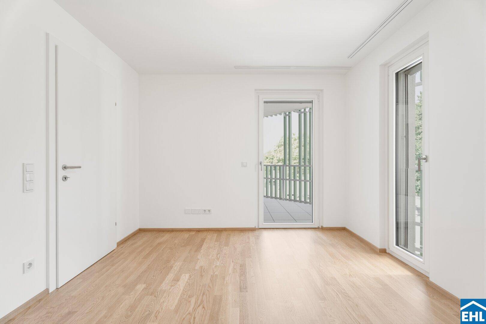 Helles Zimmer mit Parkettboden und Zugang zu einem Balkon, ideal als Schlaf- oder Arbeitszimmer.