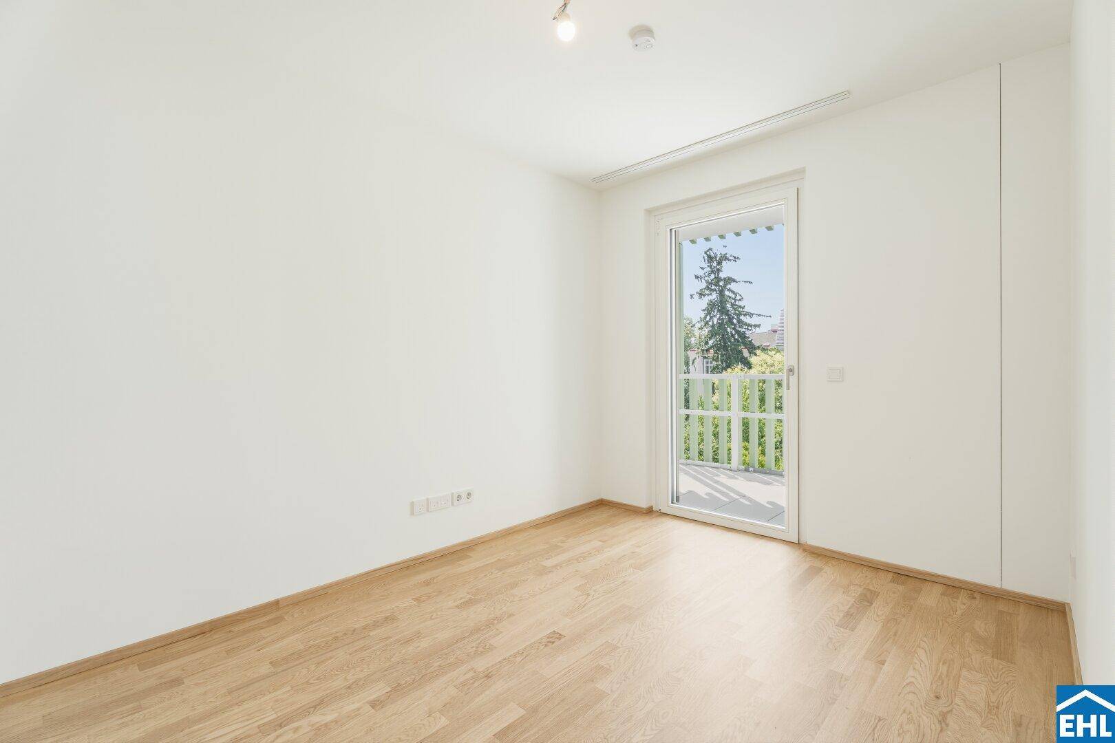 Helles Schlafzimmer mit Parkettboden und direktem Zugang zu einem privaten Balkon.