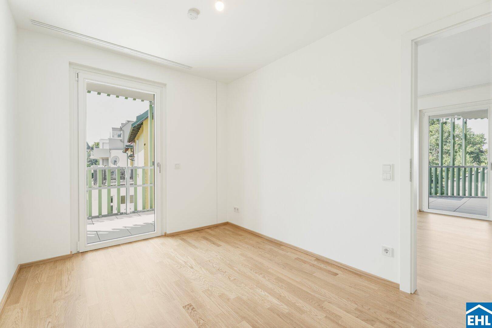 Geräumiges Schlafzimmer mit Parkettboden und Balkonzugang, bietet viel Tageslicht.