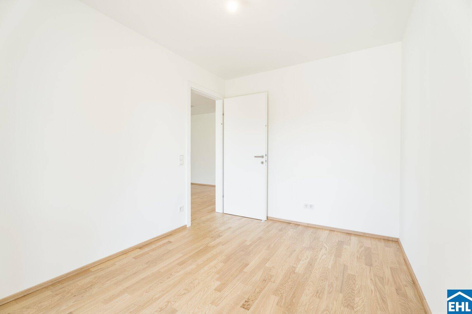 Leeres Schlafzimmer mit hellem Parkettboden und weiß gestrichenen Wänden, bereit zur Einrichtung.
