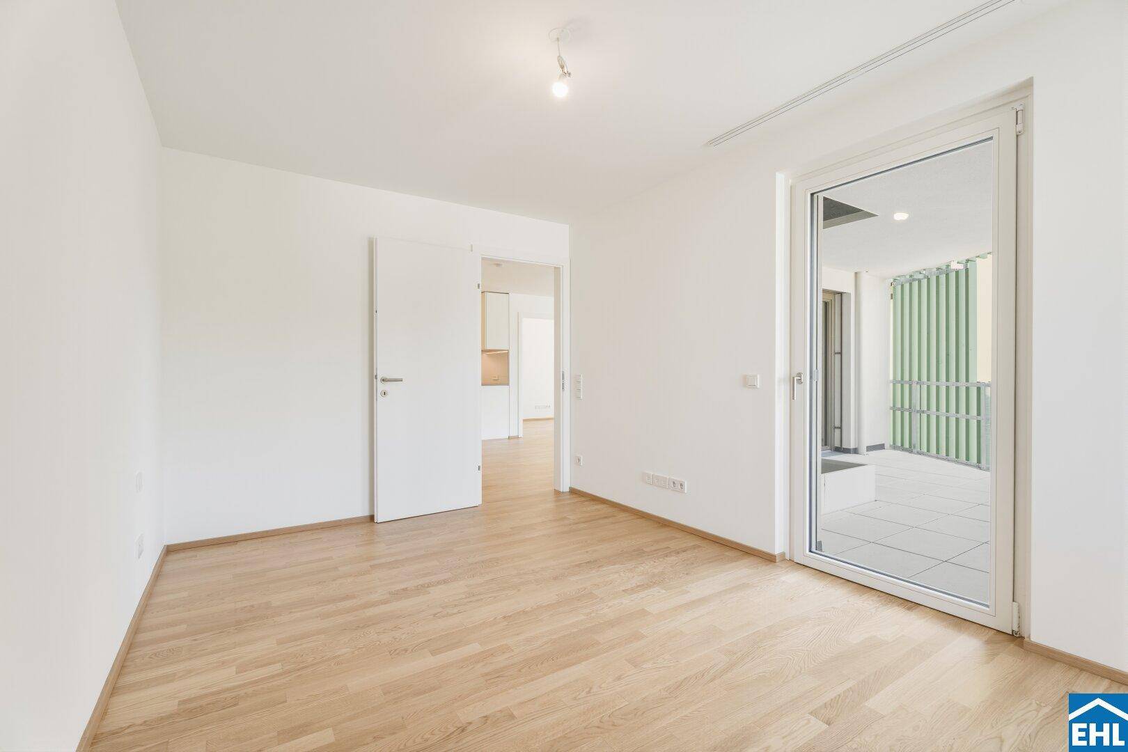 Leeres Schlafzimmer mit Parkettboden und Balkonzugang, ideal für individuelle Gestaltung.