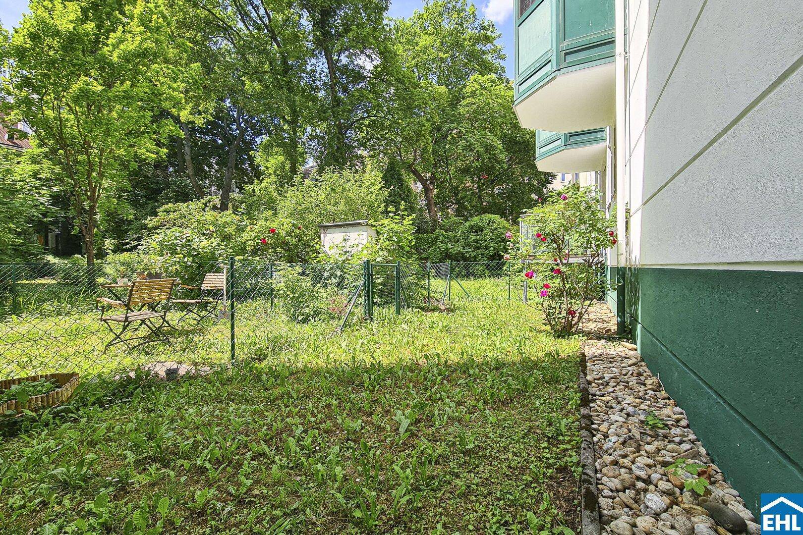 Grüner Gartenbereich mit Sitzgelegenheiten und einem kleinen Schuppen, umgeben von Bäumen.