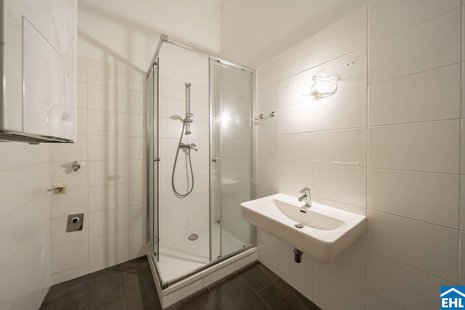 Modernes Badezimmer mit Duschkabine, Waschbecken und weißen Fliesen an den Wänden.