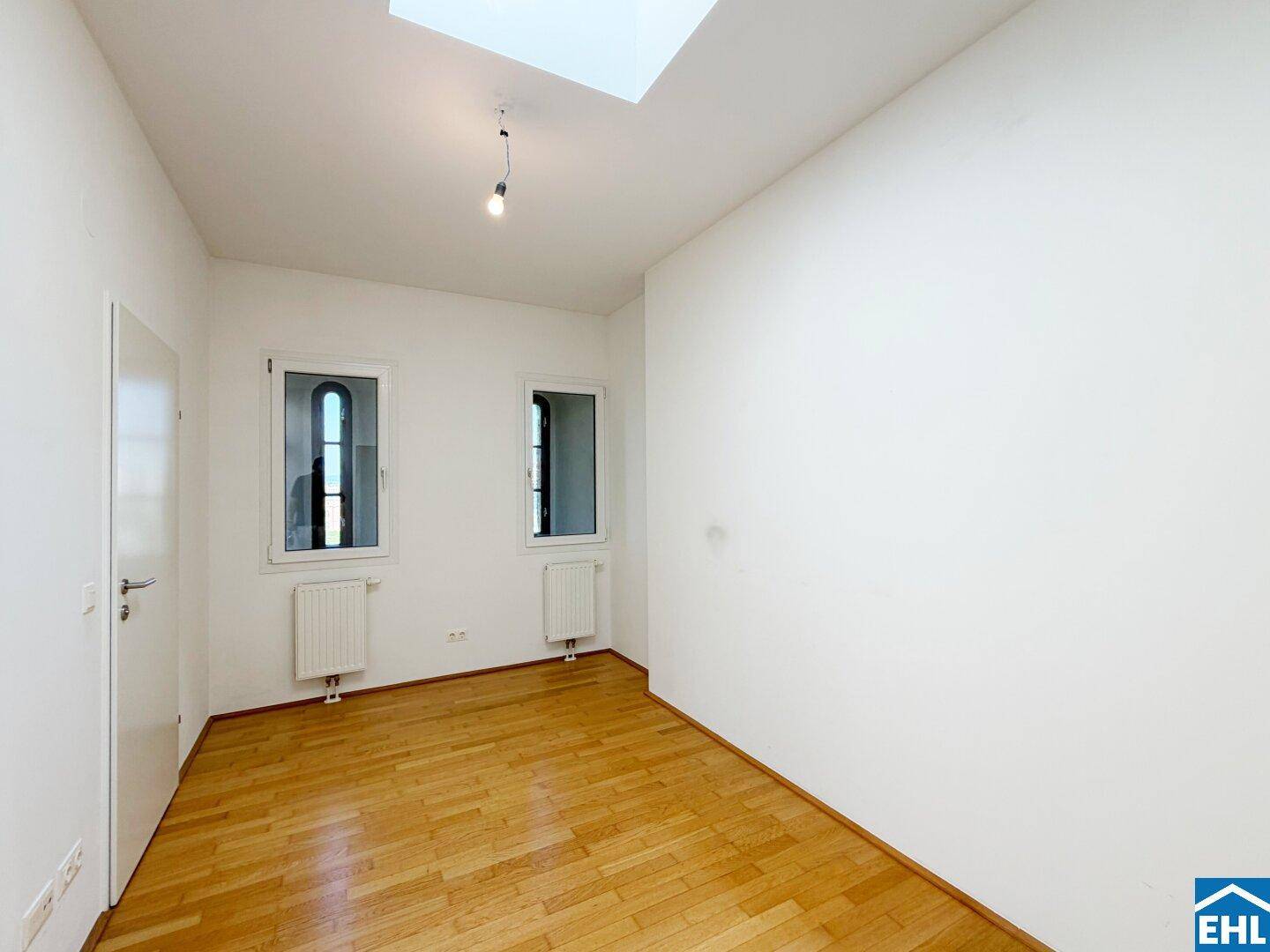 Ruhiges Schlafzimmer mit Parkettboden, zwei Fenstern und einem Oberlicht für viel Tageslicht.