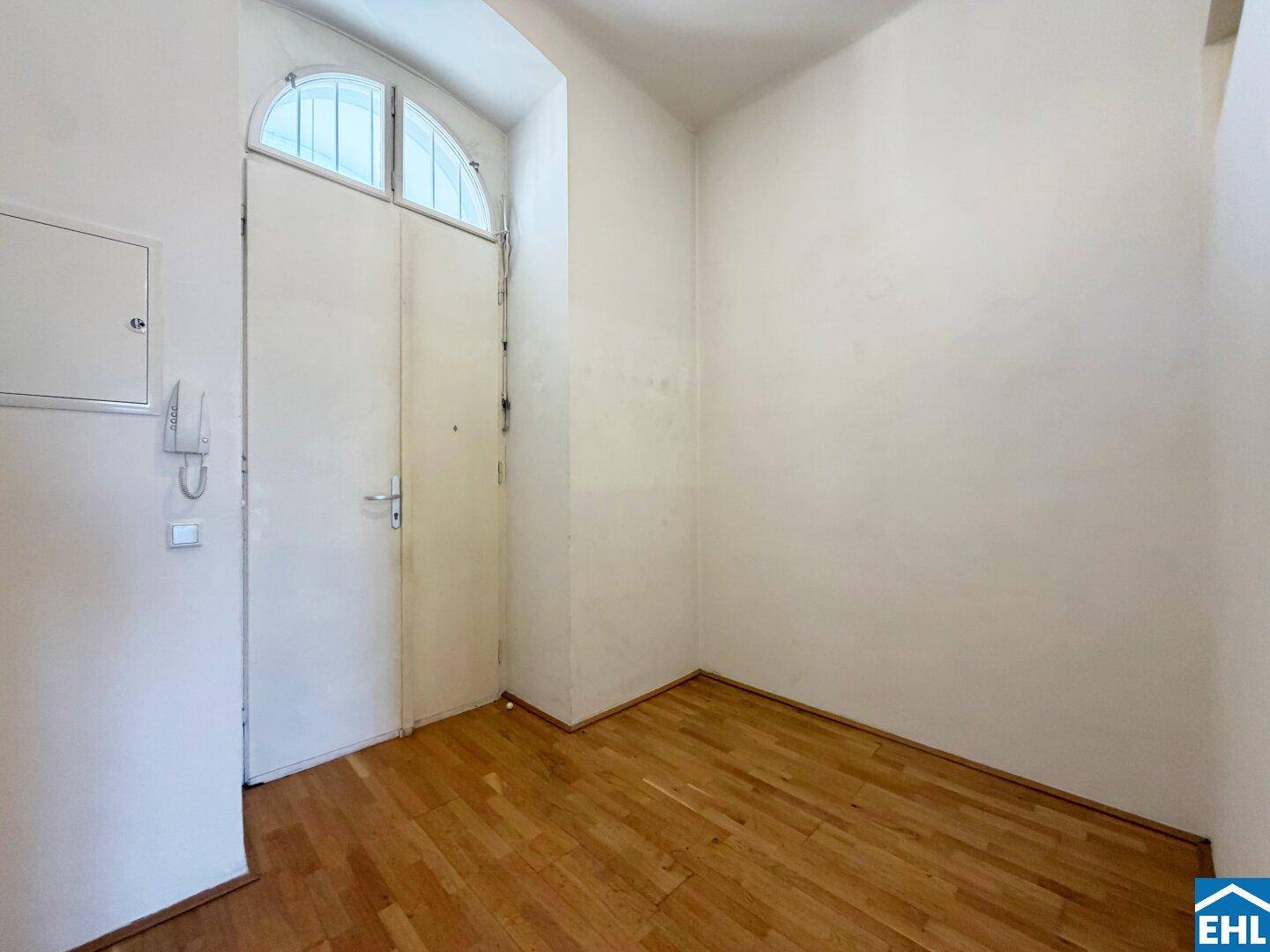 Eingangsbereich mit Holzdielenboden und einer hohen Eingangstür mit Oberlicht.