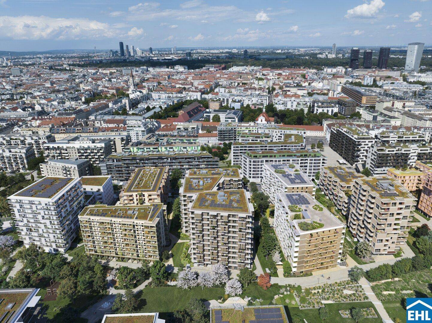 Luftaufnahme eines modernen Wohnkomplexes mit begrünten Dächern und Stadtpanorama im Hintergrund.