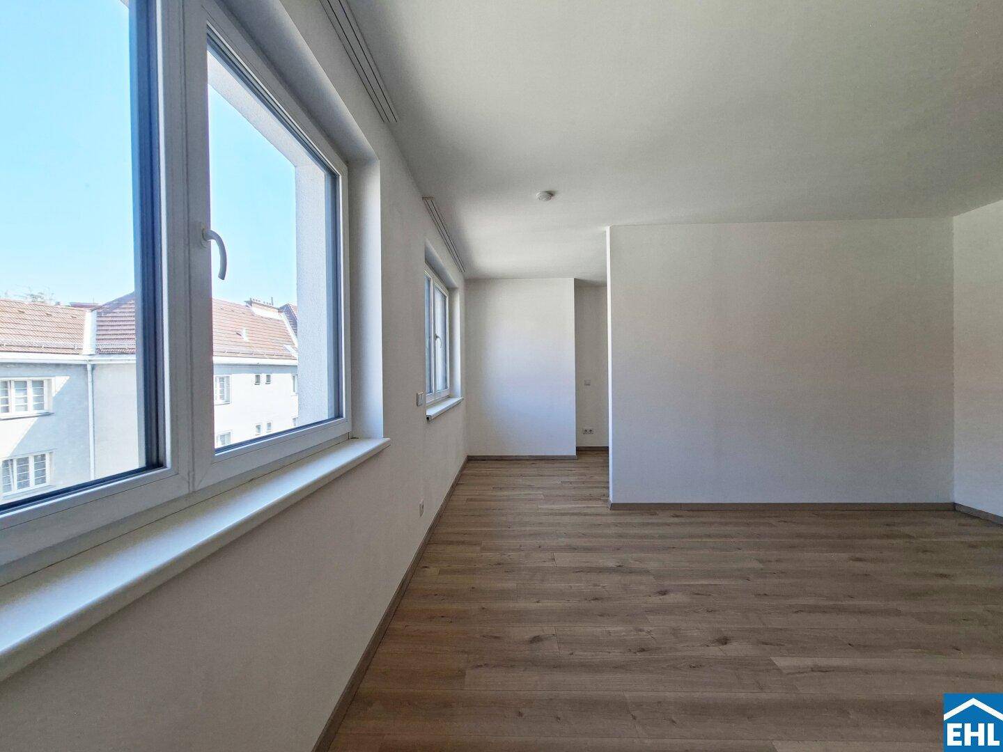 Heller Wohnraum mit großen Fenstern, die viel Tageslicht hereinlassen und einen Blick nach draußen bieten.