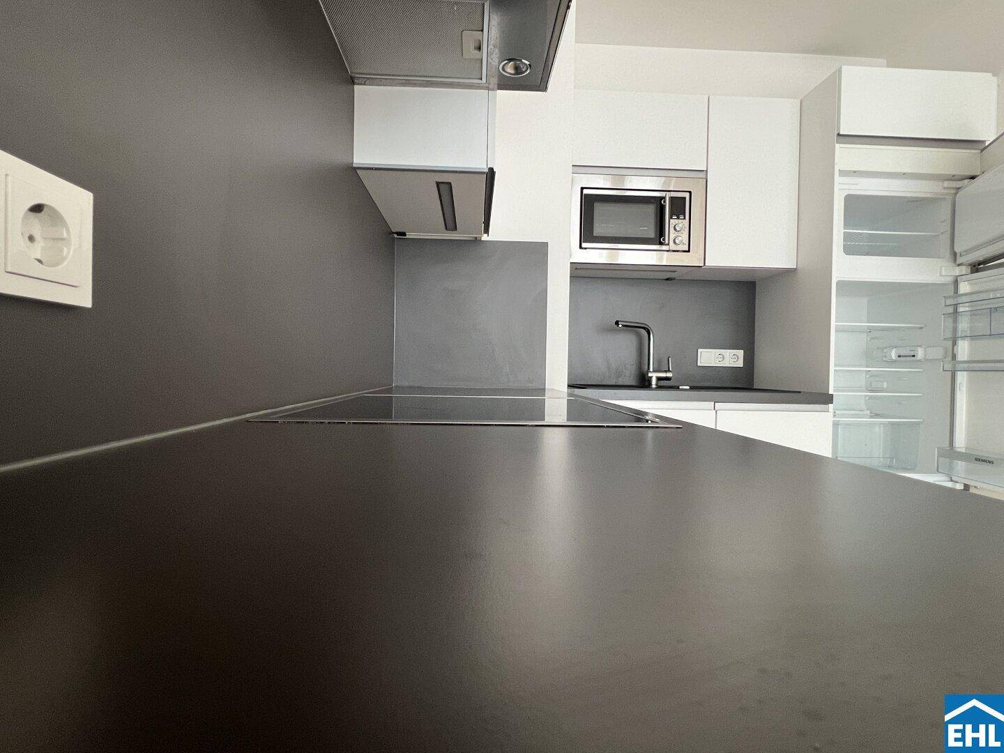 Küchenarbeitsplatte mit Spüle, Mikrowelle und Kühlschrank in einer modernen Einbauküche.