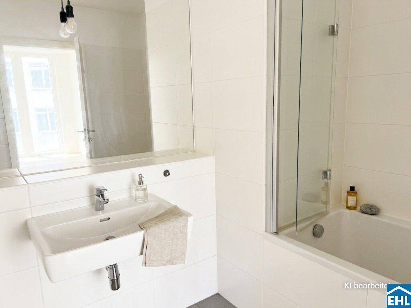Helles Badezimmer mit Waschbecken, großem Spiegel und Dusch-Badewannen-Kombination, weiß gefliest.