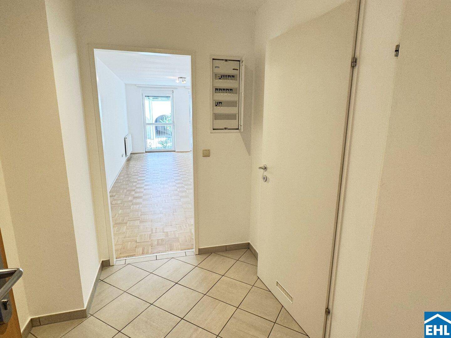 Eingangsbereich mit Fliesenboden und Blick in den offenen Wohnbereich der Wohnung.