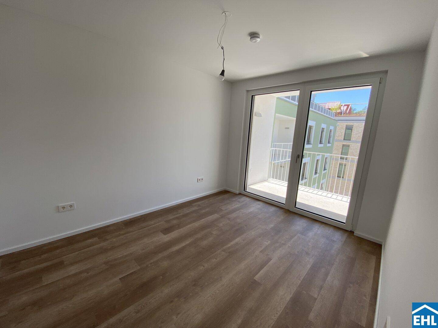 Helles Zimmer mit Laminatboden und großem Balkonzugang, ideal als Schlafzimmer.