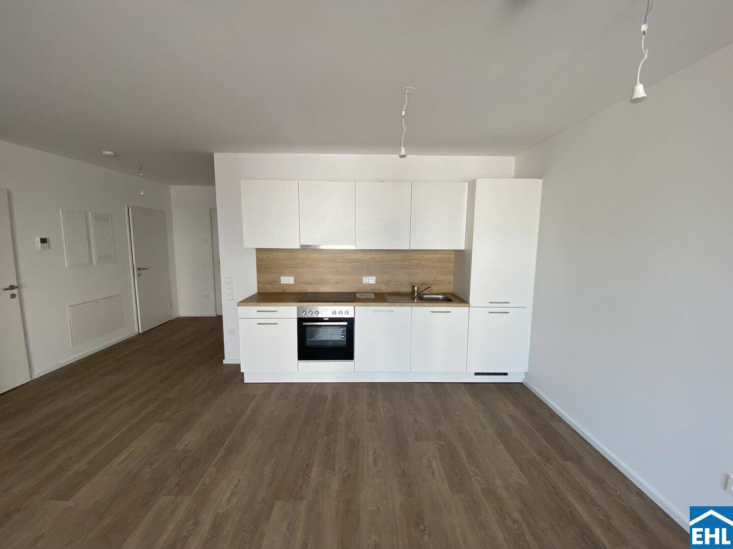 Moderne Einbauküche mit weißen Schränken, Holzoptik-Arbeitsplatte und integrierten Geräten.