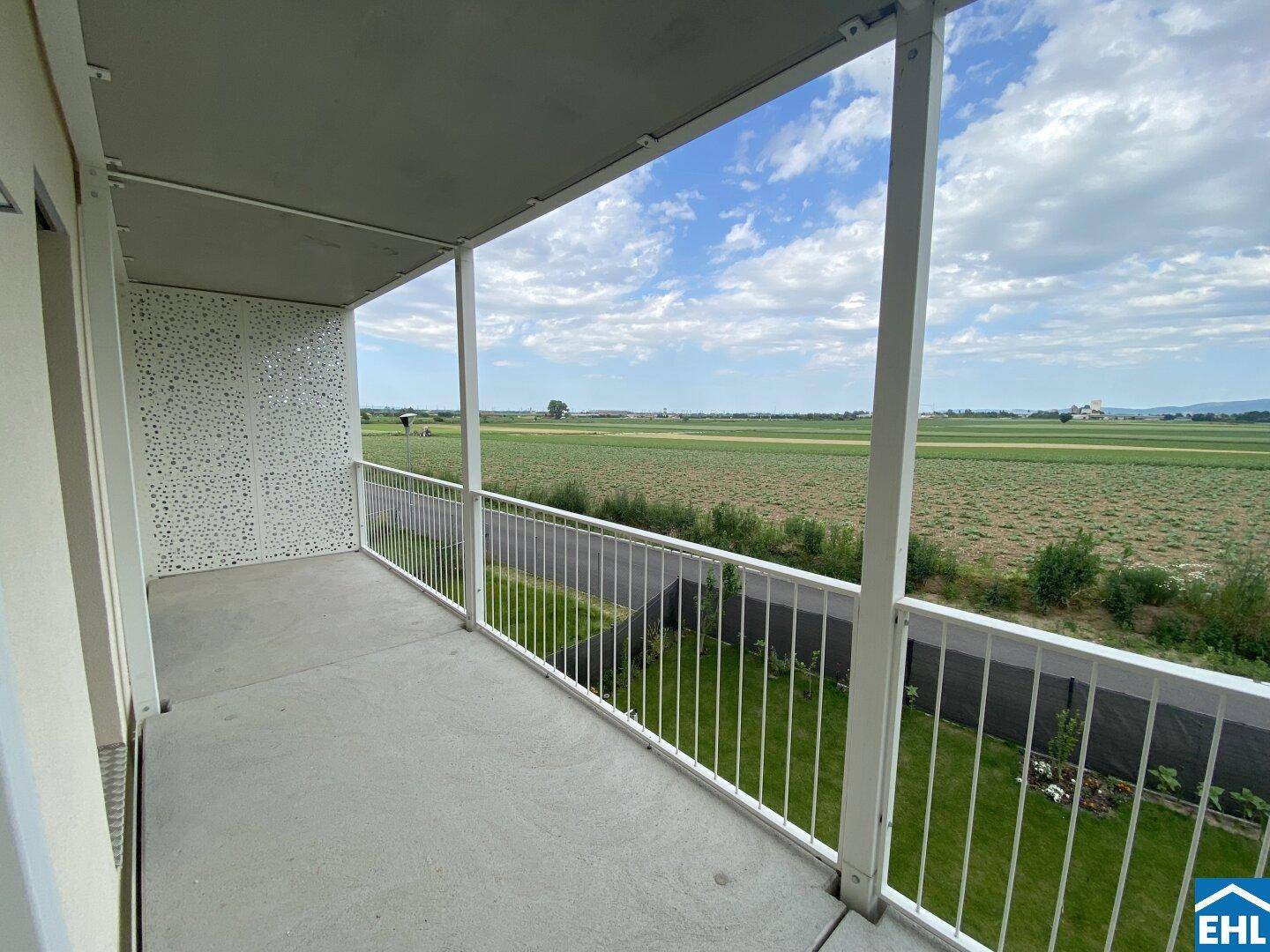 Geräumiger Balkon mit weitem Blick über grüne Felder und die umliegende Landschaft.