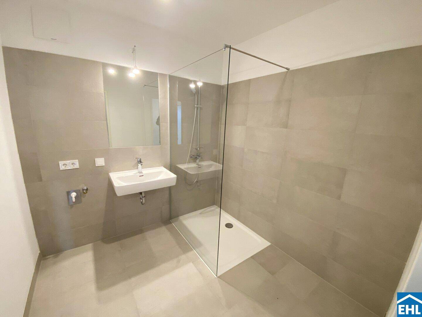 Modernes Badezimmer mit ebenerdiger Dusche, großformatigen Fliesen und Einzelwaschbecken.