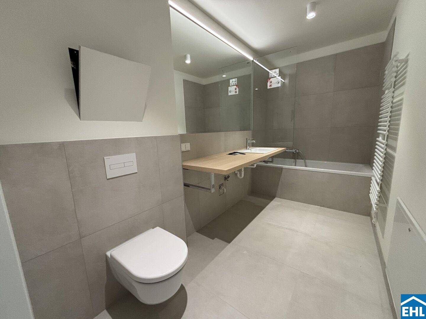 Modernes Badezimmer mit Badewanne, wandhängendem WC und beheiztem Handtuchhalter.